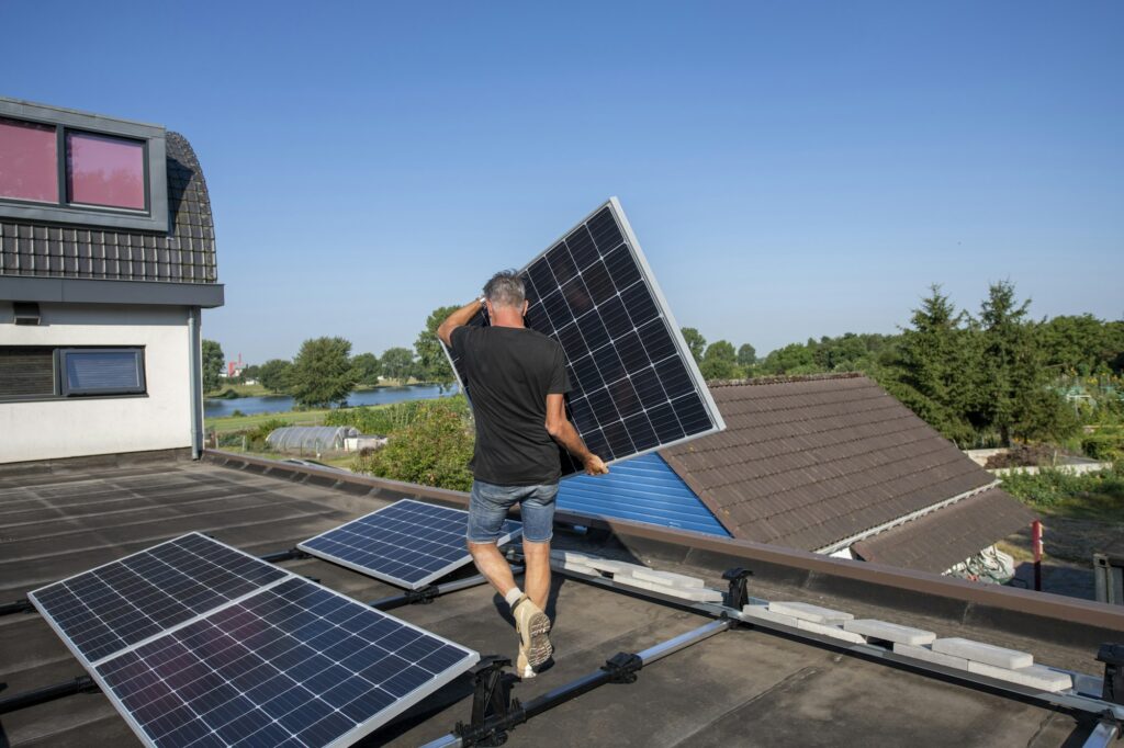 Man installing solar panels on a rooftop on a sunny day.